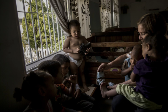  Un cuidador ayuda a un niño a vestirse en Bambi House, un orfanato privado en Caracas, Venezuela. (Alejandro Cegarra for The Washington Post)