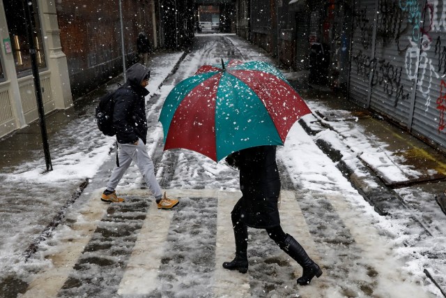 A woman walks in the snow during a winter nor'easter storm in the Chinatown area of New York City, U.S., March 21, 2018. REUTERS/Brendan McDermid