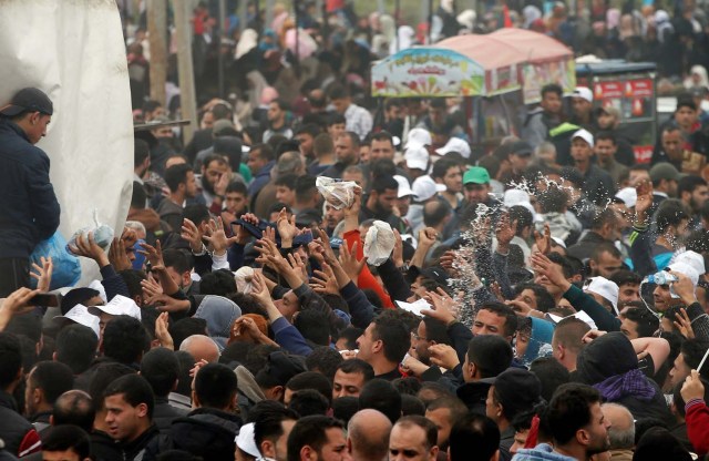 Palestinians receive food during a tent city protest along the Israel border with Gaza, demanding the right to return to their homeland, east of Gaza City March 30, 2018. REUTERS/Mohammed Salem