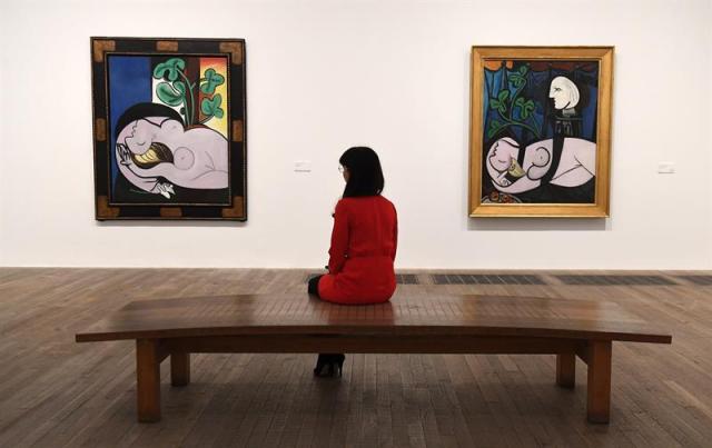 Una empleada del museo observa las obras de Pablo Picaso "Desnudo sobre un sillón negro" (izq), y "Desnudo, hojas verdes y busto", ambas de 1932, expuestas en el ámbito de la exposición inaugurada en la Tate Modern de Londres (Reino Unido) hoy, 6 de marzo de 2018. EFE/ Andy Rain