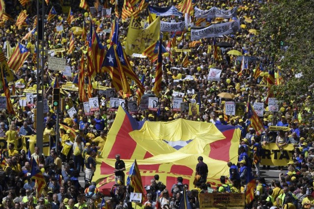 People unfold a big Catalan pro-independence 'estelada' flag with a yellow ribbon on it during a demonstration to support Catalan pro-independence jailed leaders and politicians and called by 'Espai Democracia i Convivencia' platform that groups separatist collectives and unions in Barcelona on April 15, 2018.  Thousands of people marched in Barcelona today to protest the jailing of nine Catalan separatist leaders facing trial on "rebellion" charges. Many chanted "Freedom for the political prisoners" as they massed on the Parallel Avenue, one of the city's main streets, wearing yellow scarves, sweaters or jackets -- the colour chosen to show solidarity with the jailed leaders.  / AFP PHOTO / LLUIS GENE
