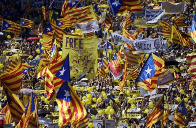 People wave Catalan pro-independence 'estelada' flags during a demonstration to support Catalan pro-independence jailed leaders and politicians and called by 'Espai Democracia i Convivencia' platform that groups separatist collectives and unions in Barcelona on April 15, 2018.  Thousands of people marched in Barcelona today to protest the jailing of nine Catalan separatist leaders facing trial on "rebellion" charges. Many chanted "Freedom for the political prisoners" as they massed on the Parallel Avenue, one of the city's main streets, wearing yellow scarves, sweaters or jackets -- the colour chosen to show solidarity with the jailed leaders.  / AFP PHOTO / LLUIS GENE