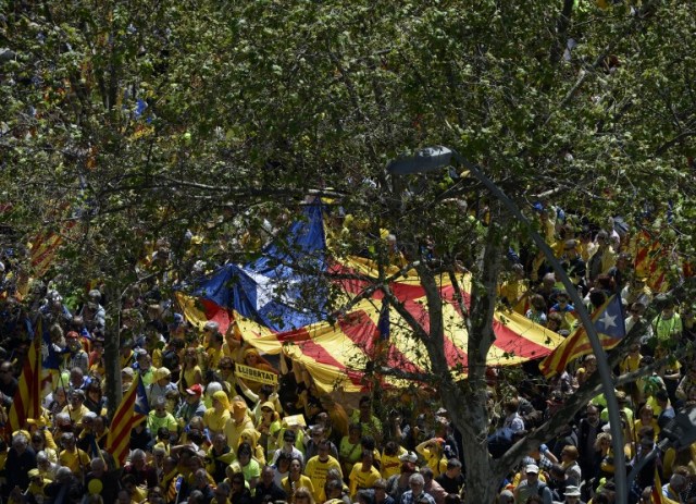 People carry a big Catalan pro-independence 'estelada' flag during a demonstration to support Catalan pro-independence jailed leaders and politicians and called by 'Espai Democracia i Convivencia' platform that groups separatist collectives and unions in Barcelona on April 15, 2018.  Thousands of people marched in Barcelona today to protest the jailing of nine Catalan separatist leaders facing trial on "rebellion" charges. Many chanted "Freedom for the political prisoners" as they massed on the Parallel Avenue, one of the city's main streets, wearing yellow scarves, sweaters or jackets -- the colour chosen to show solidarity with the jailed leaders.  / AFP PHOTO / Josep LAGO