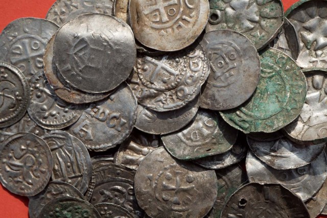 Saxon, Ottonian, Danish and Byzantine coins are pictured on a table in Schaprode, northern Germany on April 13, 2018. A 13-year-old boy and a hobby archaeologist have unearthed a "significant" trove in Germany which may have belonged to the legendary Danish king Harald Bluetooth who brought Christianity to Denmark. A dig covering 400 square metres (4,300 square feet) that finally started over the weekend by the regional archaeology service has since uncovered a trove believed linked to the Danish king who reigned from around 958 to 986. Braided necklaces, pearls, brooches, a Thor's hammer, rings and up to 600 chipped coins were found, including more than 100 that date back to Bluetooth's era. / AFP PHOTO / dpa / Stefan Sauer / Germany OUT