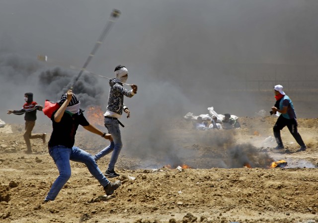 Los manifestantes palestinos utilizan hondas para arrojar piedras contra las fuerzas de seguridad israelíes durante los enfrentamientos cerca de la frontera entre Israel y la Franja de Gaza, al este de Jabalia, el 14 de mayo de 2018, mientras protestan por la inauguración de la embajada de Estados Unidos tras su controvertido traslado a Jerusalén. / AFP PHOTO / MOHAMMED ABED