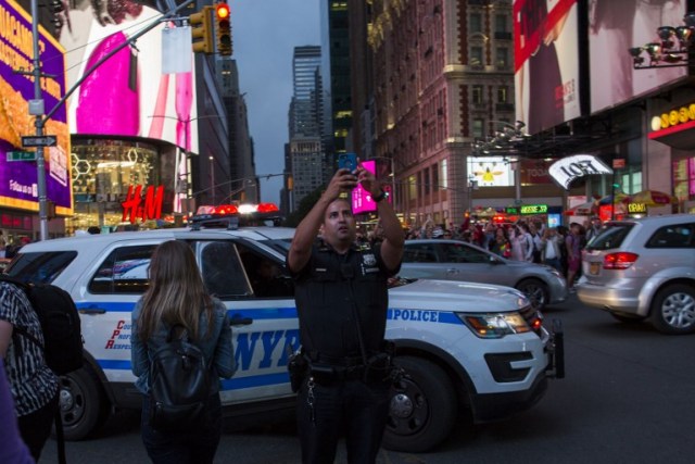 NUEVA YORK, NY - 30 DE MAYO: El oficial del NYPD toma imágenes del fenómeno conocido como Manhattanhenge en Times Square 42nd Street el 30 de mayo de 2018 en la ciudad de Nueva York. Manhattanhenge, o el solsticio de Manhattan, ocurre dos veces al año cuando el sol está alineado con las calles este-oeste de la red principal de Manhattan Eduardo Muñoz Álvarez / Getty Images / AFP