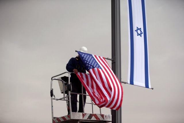 Un trabajador con una grúa cuelga una bandera de EE. UU. Al lado de una bandera israelí, al lado de la entrada al consulado de EE. UU. En Jerusalén, el 7 de mayo de 2018. REUTERS / Ronen Zvulun / Archivo de foto