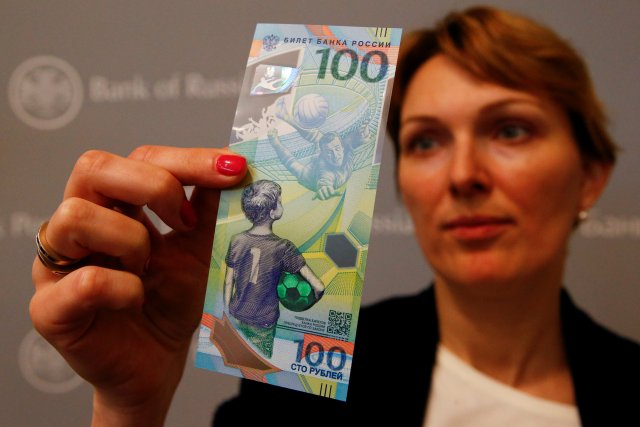 Un empleado tiene el billete de 100 rublos recientemente diseñado dedicado a la Copa Mundial de la FIFA 2018, durante una conferencia de prensa en Moscú, Rusia, el 22 de mayo de 2018. REUTERS / Sergei Karpukhin