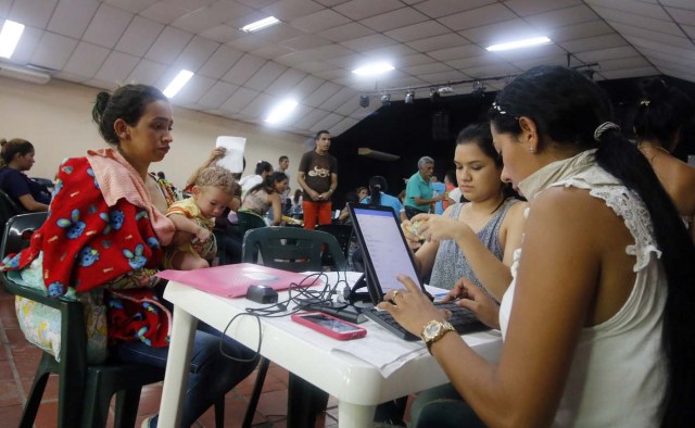 CUC07. CÚCUTA (COLOMBIA), 04/05/2018.- Un grupo de venezolanos recibe asistencia en Cúcuta (Colombia) este 3 de mayo de 2018. Bajo el sol intenso de la ciudad colombiana de Cúcuta, cientos de familias venezolanas que huyeron de su país por la crisis económica y política hacen fila para reclamar los bonos alimentarios que entrega el Programa Mundial de Alimentos (PMA) de la ONU en las zonas de frontera. El proyecto que comenzó este lunes en Cúcuta, capital de Norte de Santander, surge como la primera gran respuesta de la comunidad internacional al delicado estado alimentario del 90 % de los cerca de 35.000 venezolanos que cruzan a diario las fronteras con Colombia en busca de oportunidades. EFE/SCHNEYDER MENDOZA