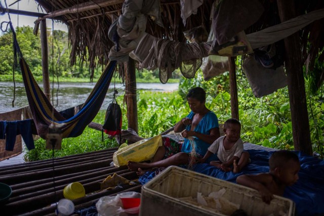 Fotografía fechada el 10 de mayo de 2018 que muestra a una mujer de la etnia Warao junto a sus hijos, en su palafito (vivienda Warao) en la ribera del río Morichal, en Maturín (Venezuela). Unos 120 indígenas distribuidos en cerca de 30 palafitos de precaria elaboración conforman la comunidad de Morichal Largo, un asentamiento de la etnia Warao ubicado en el sur de Venezuela, que resiste debajo de un puente la miseria e insalubridad propia de la crisis nacional. EFE/Cristian Hernández